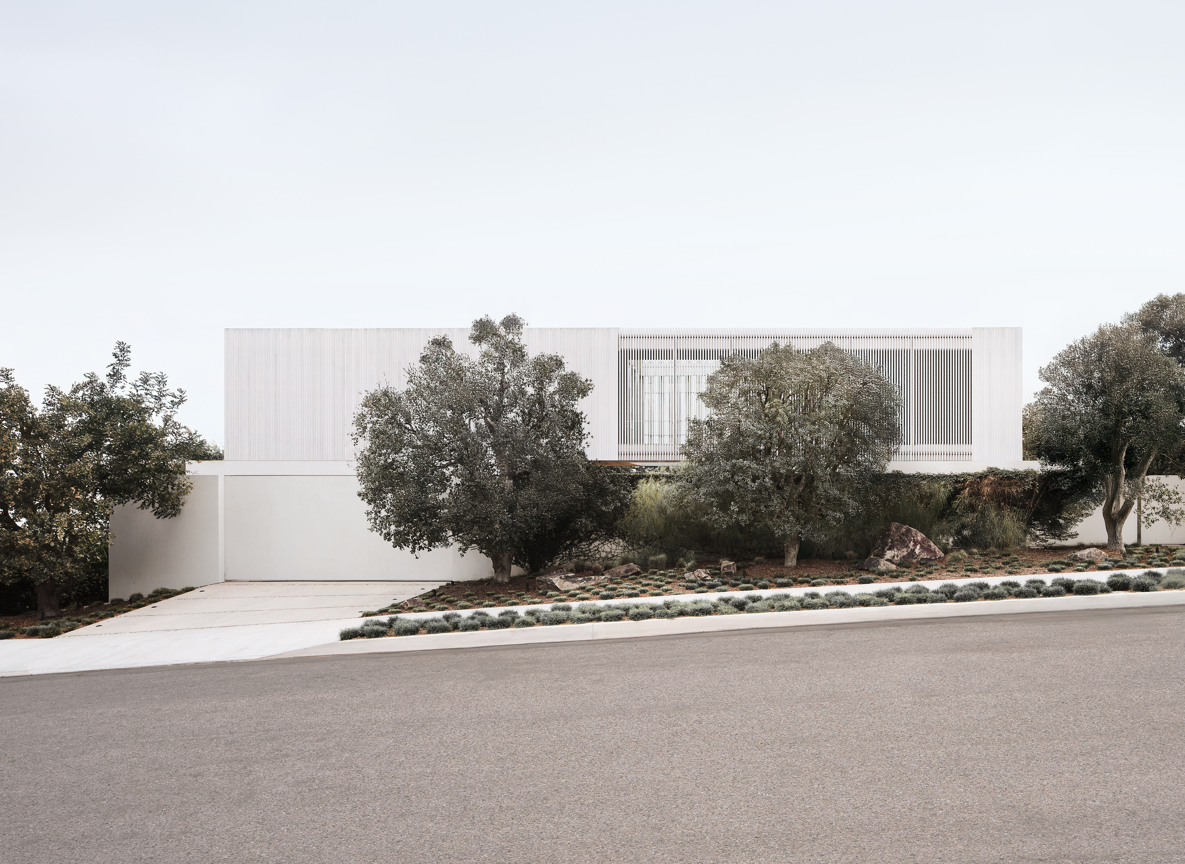 Contemporary hillside home with minimalist white facade and native landscaping, listed by Bernie Leung